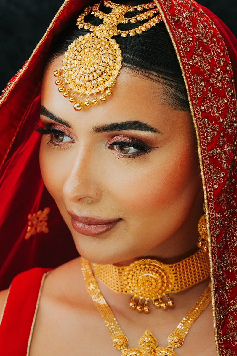 Bride in a red veil wearing a 22k gold choker with a pendant, Sonei Jewellers Surrey