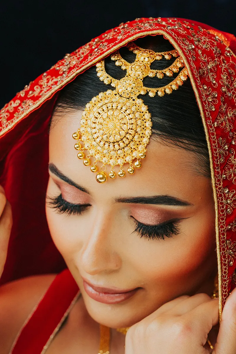 Bride in a red veil wearing a gold maang tikka, Sonei Jewellers Surrey