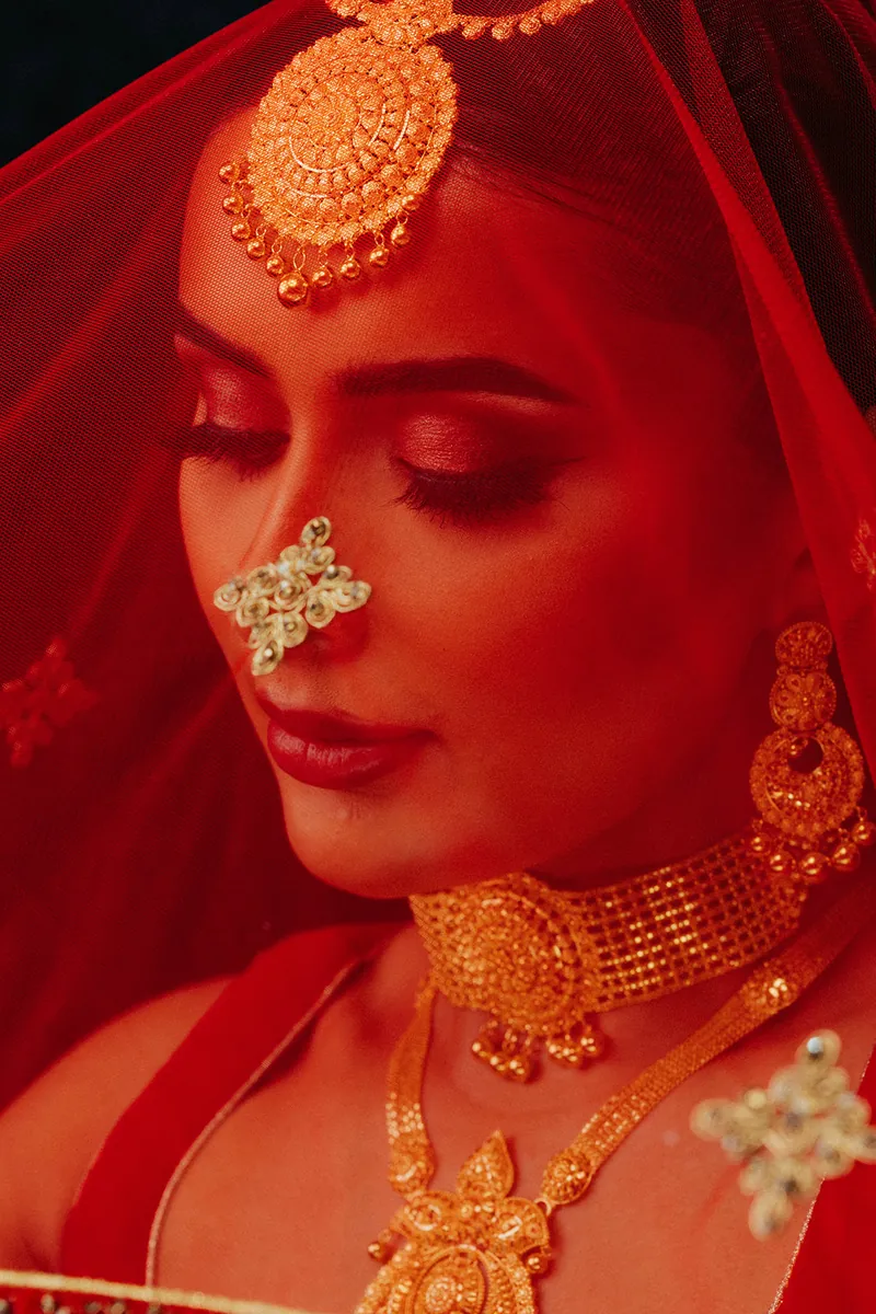 Bride in a red veil wearing a gold nose ring and necklace, Sonei Jewellers Surrey