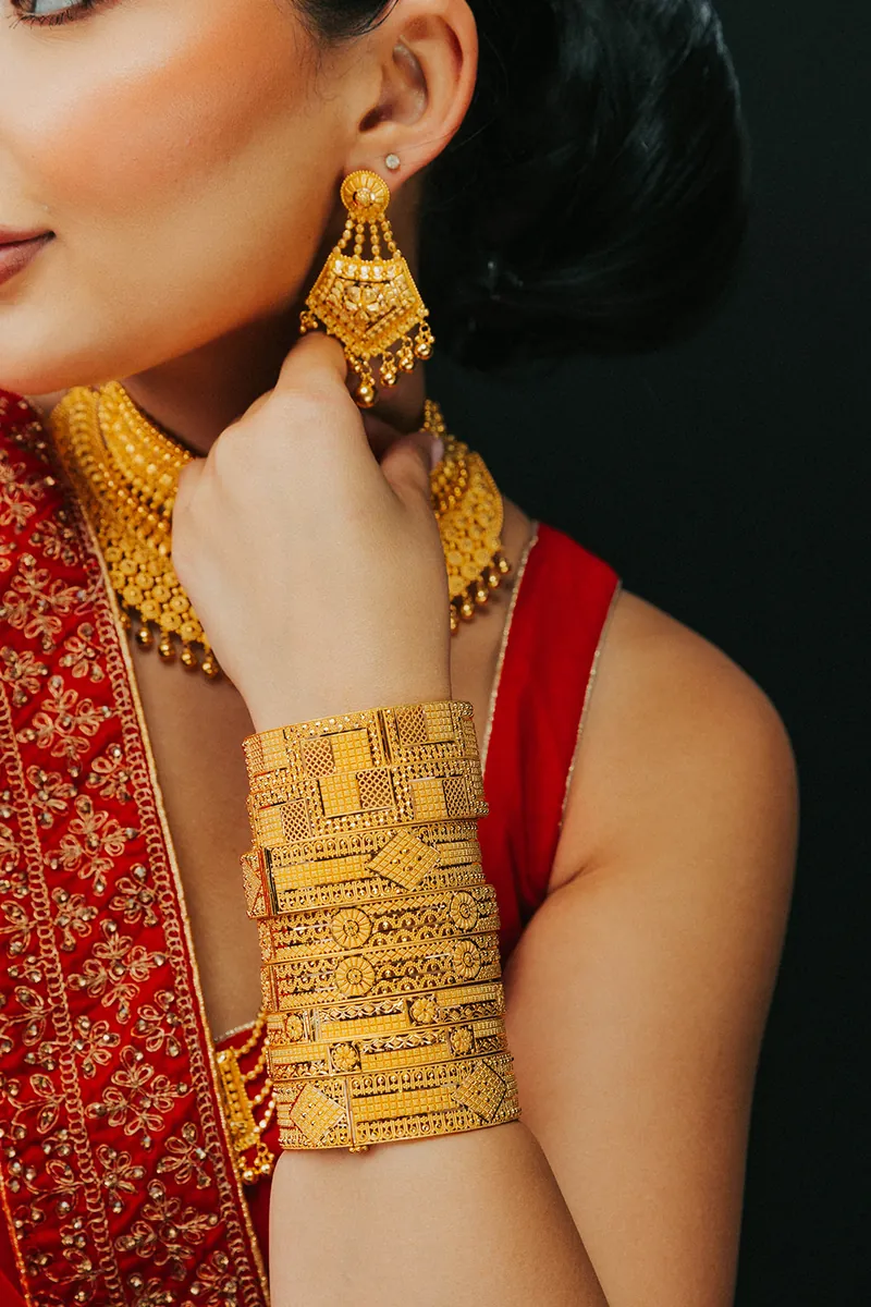 Model wearing a stack of 22k gold bangles, Sonei Jewellers Surrey
